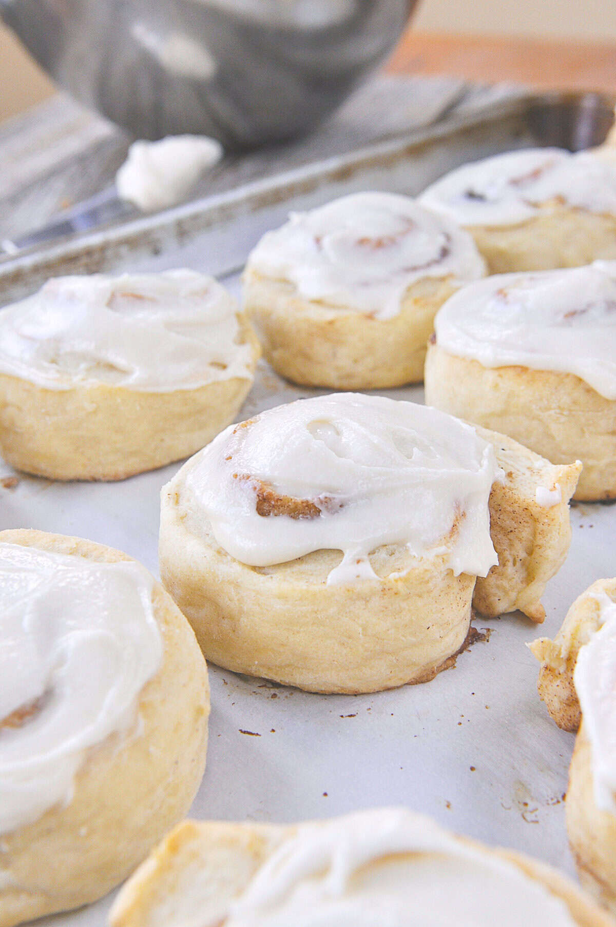 frosted cinnamon rolls on a baking sheet