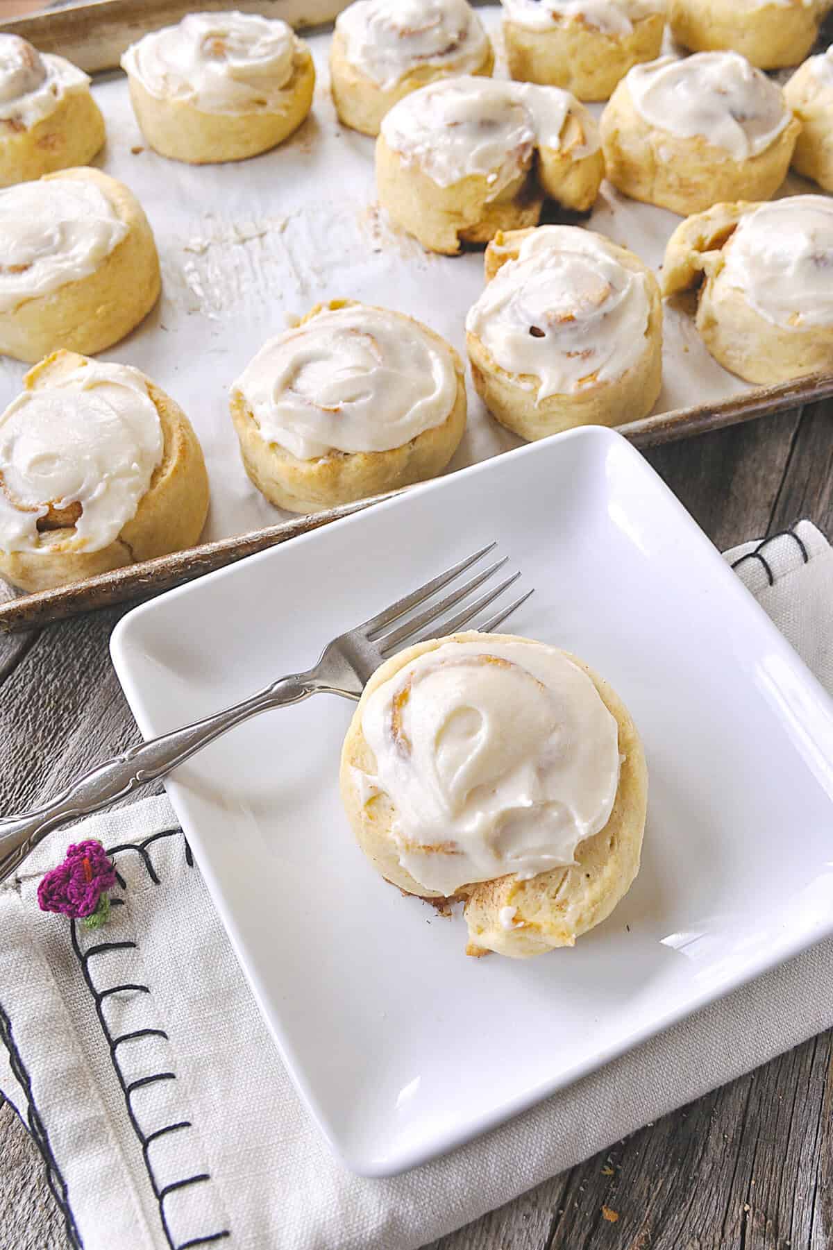 baked and frosted cinnamon roll biscuits on a plate