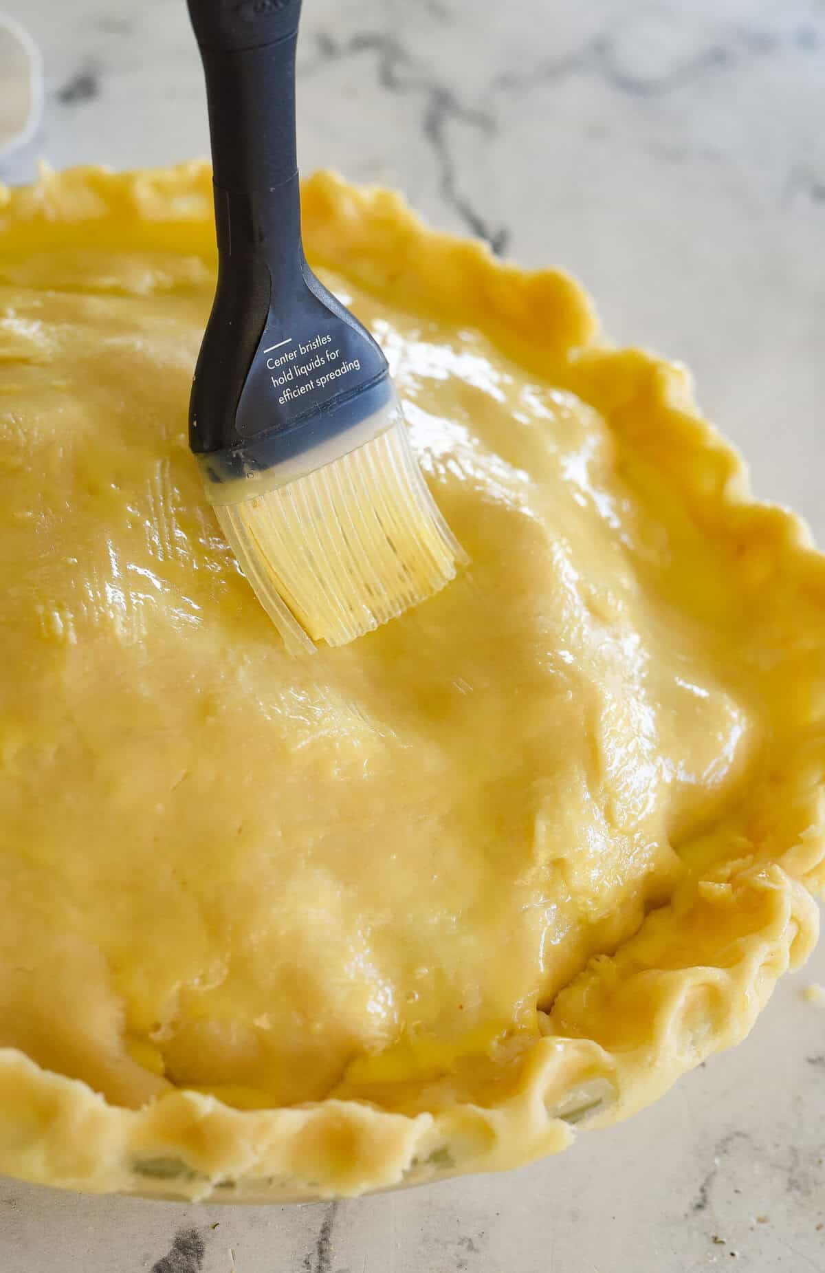 brushing pie crust with egg mixture