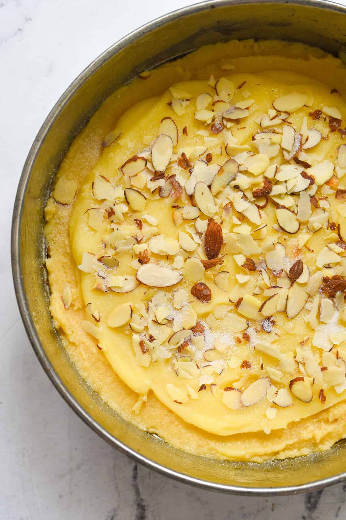 lemon almond cake batter in pan with almonds on top