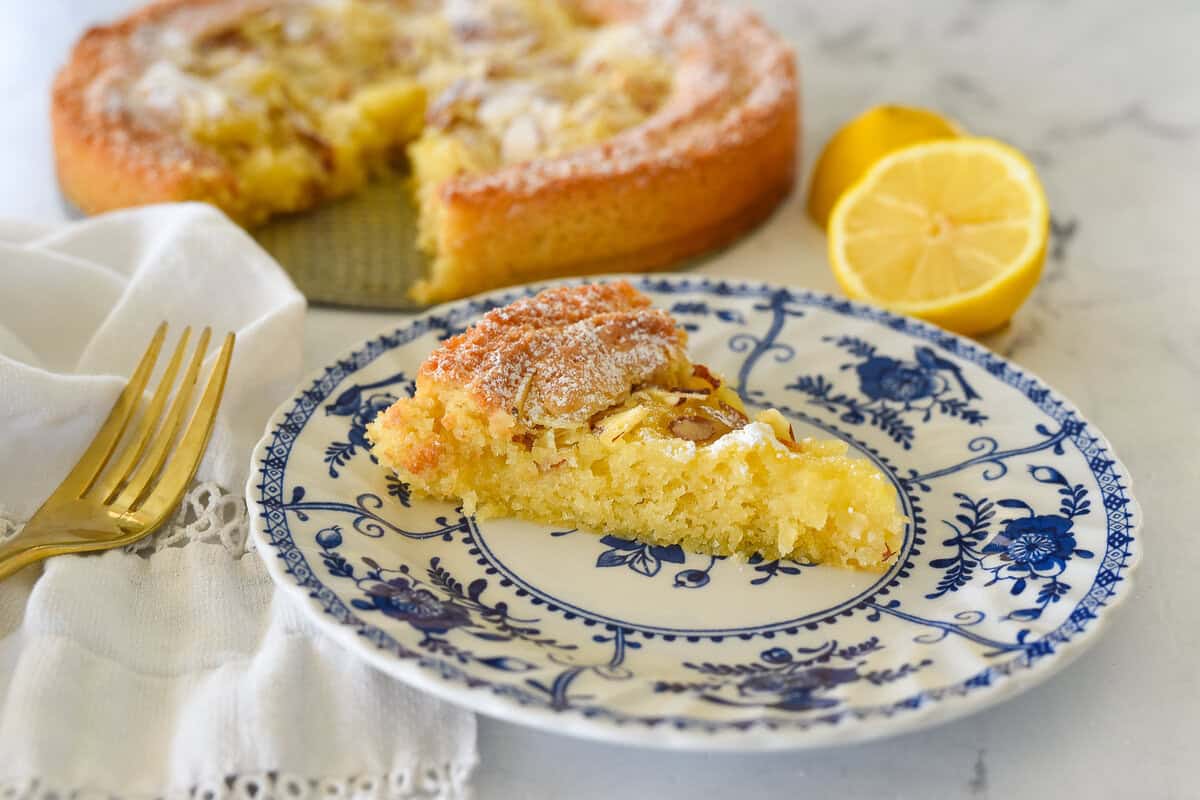 sliced lemon almond butter cake on a blue and white plate