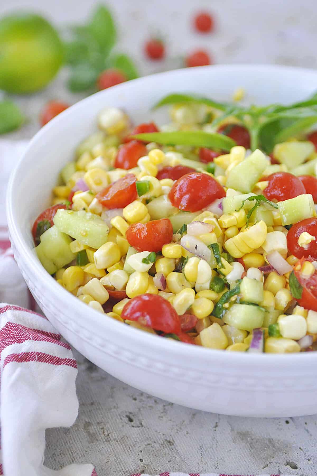 white bowl of corn salad with tomatoes in it