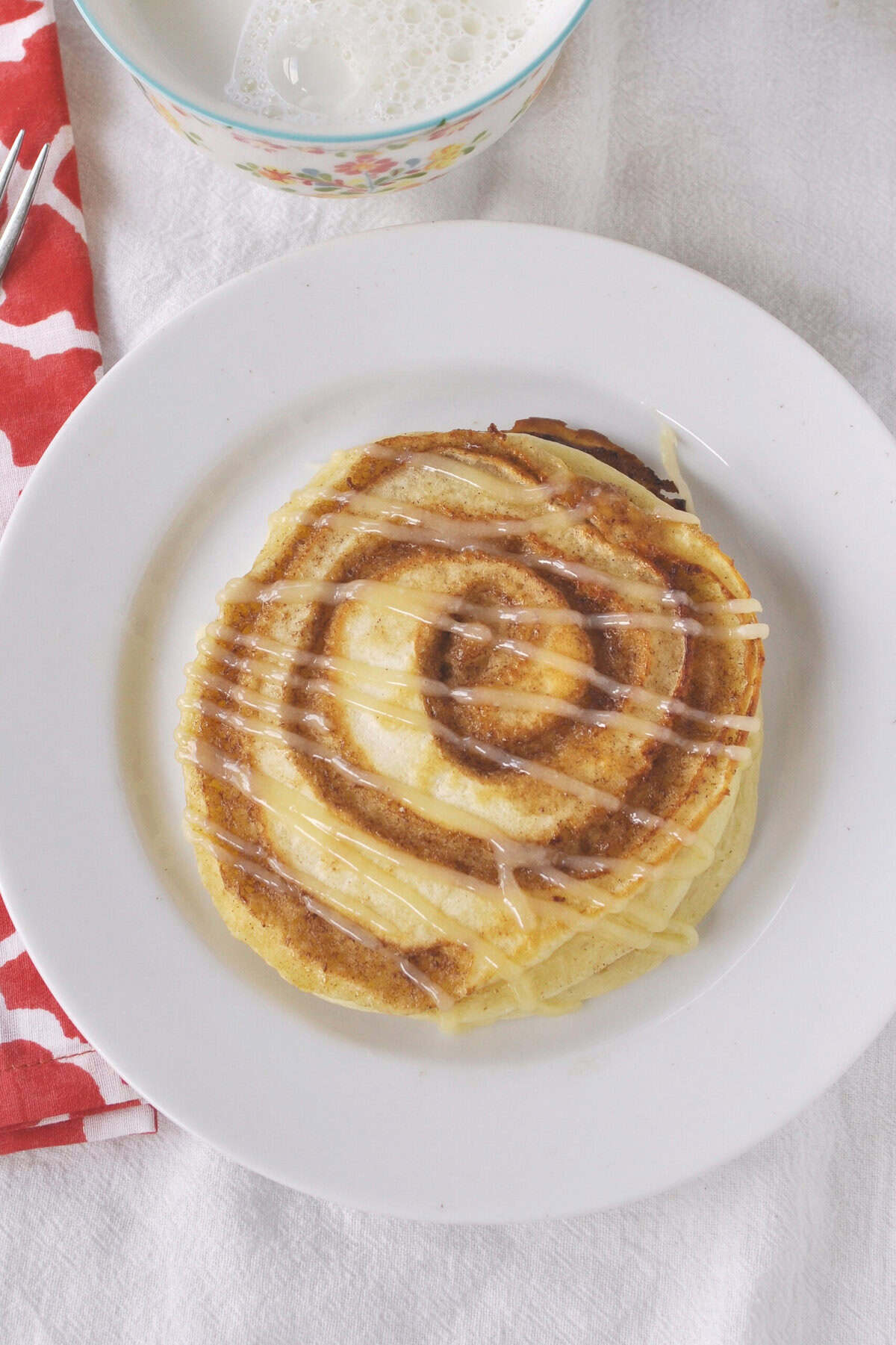 overhead shot of a cinnamon roll pancake on a white plate