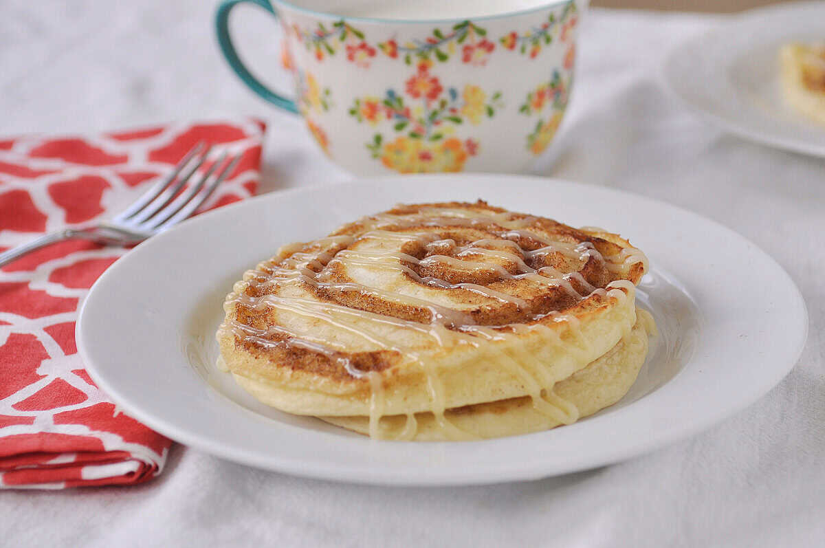 CINNAMON ROLL PANCAKES ON A WHITE PLATE