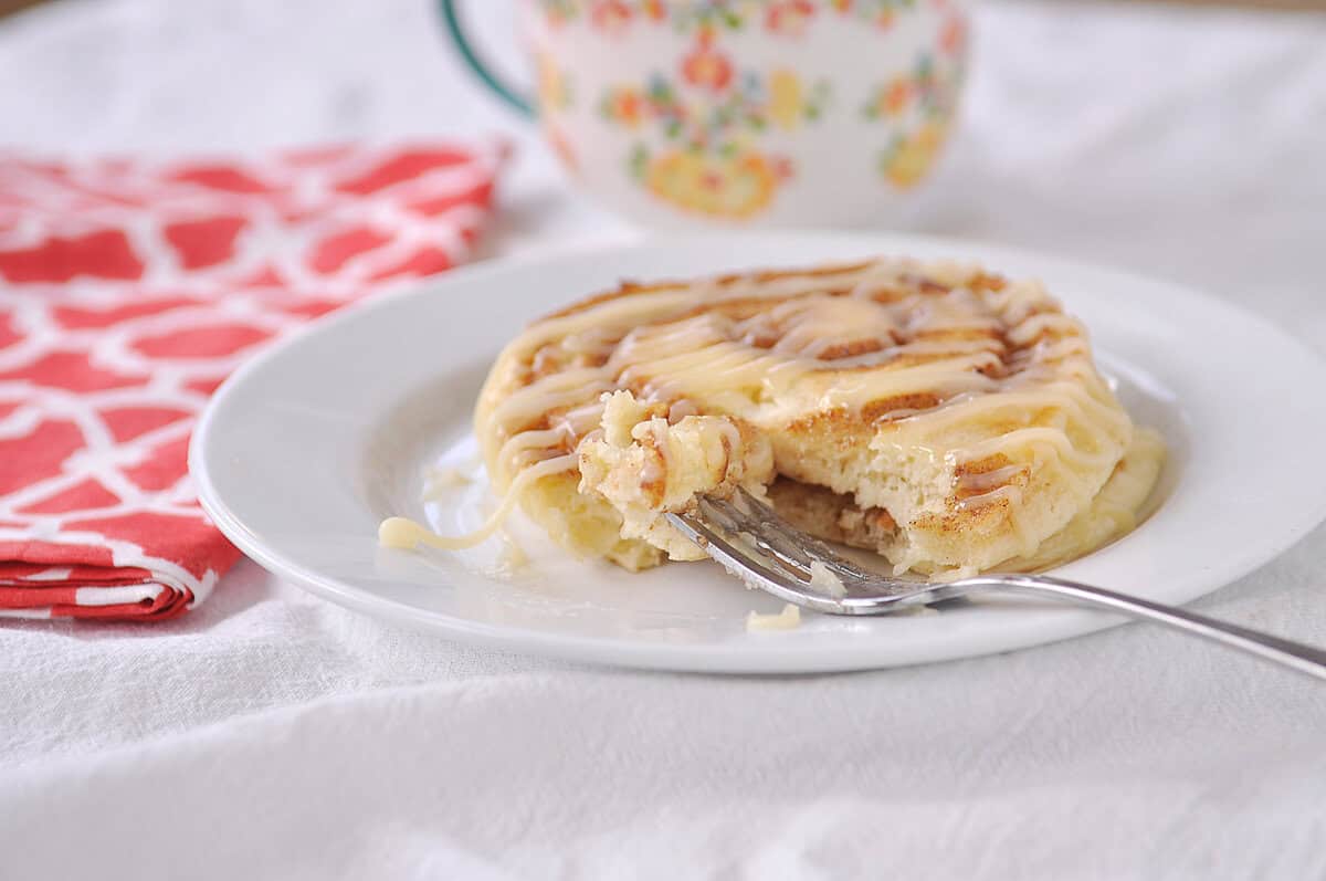 cinnamon roll pancake on a white plate with a fork